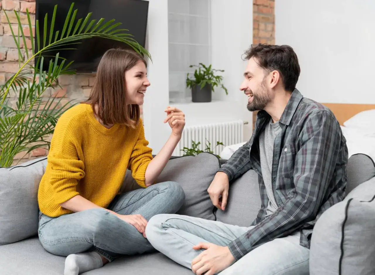 Pareja riendo en el sof&aacute;, aprendiendo como expresar sentimientos.