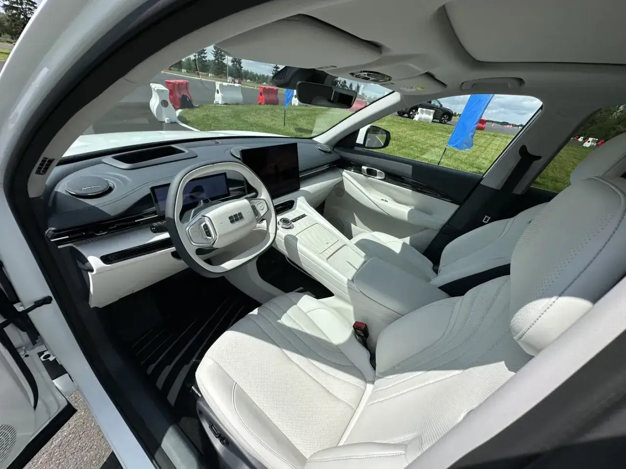 Wnętrze białego Geely EX5 z jasną tapicerką, dużym ekranem i nowoczesną kierownicą.