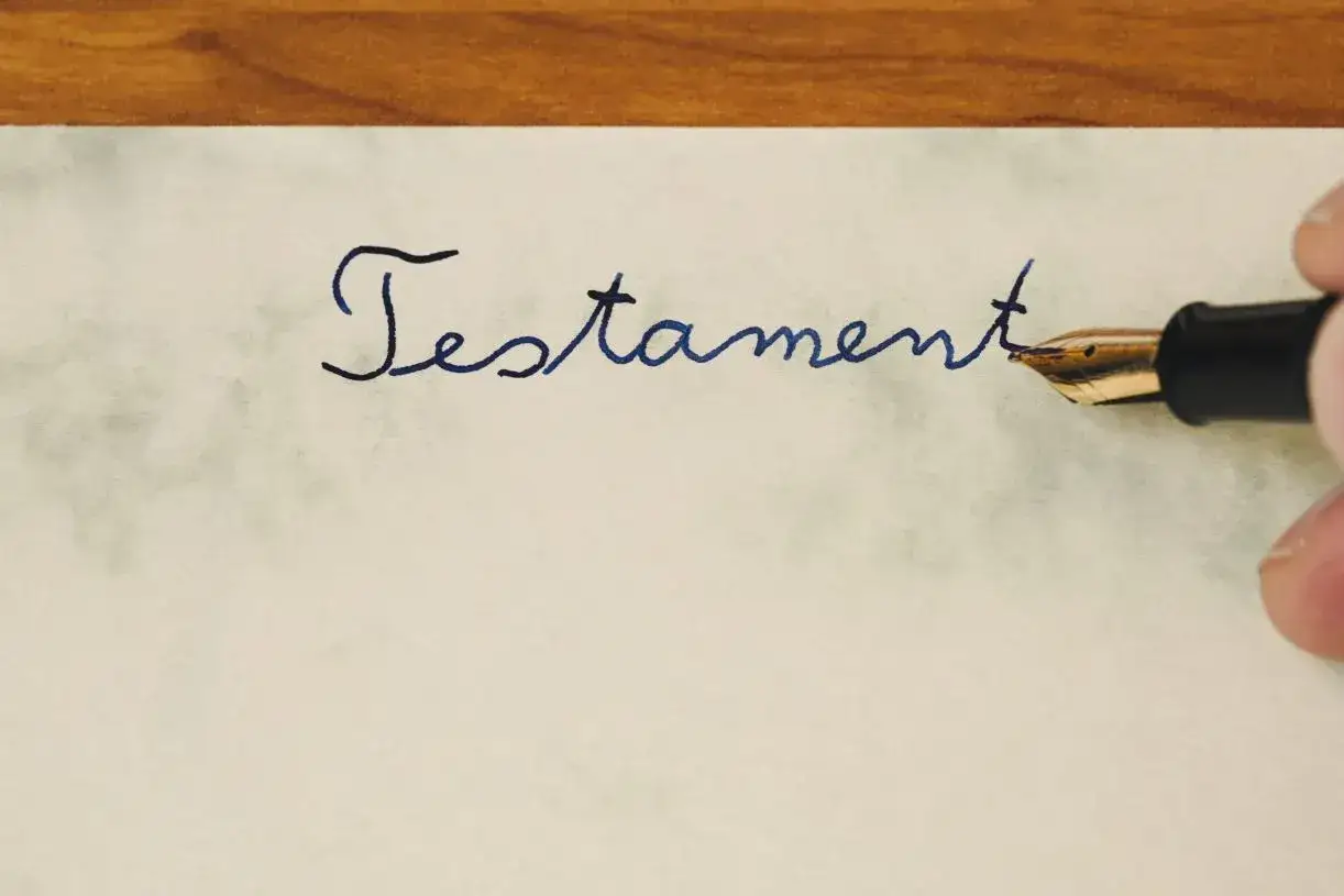 Dłoń pisze atramentowym pi&oacute;rem słowo 