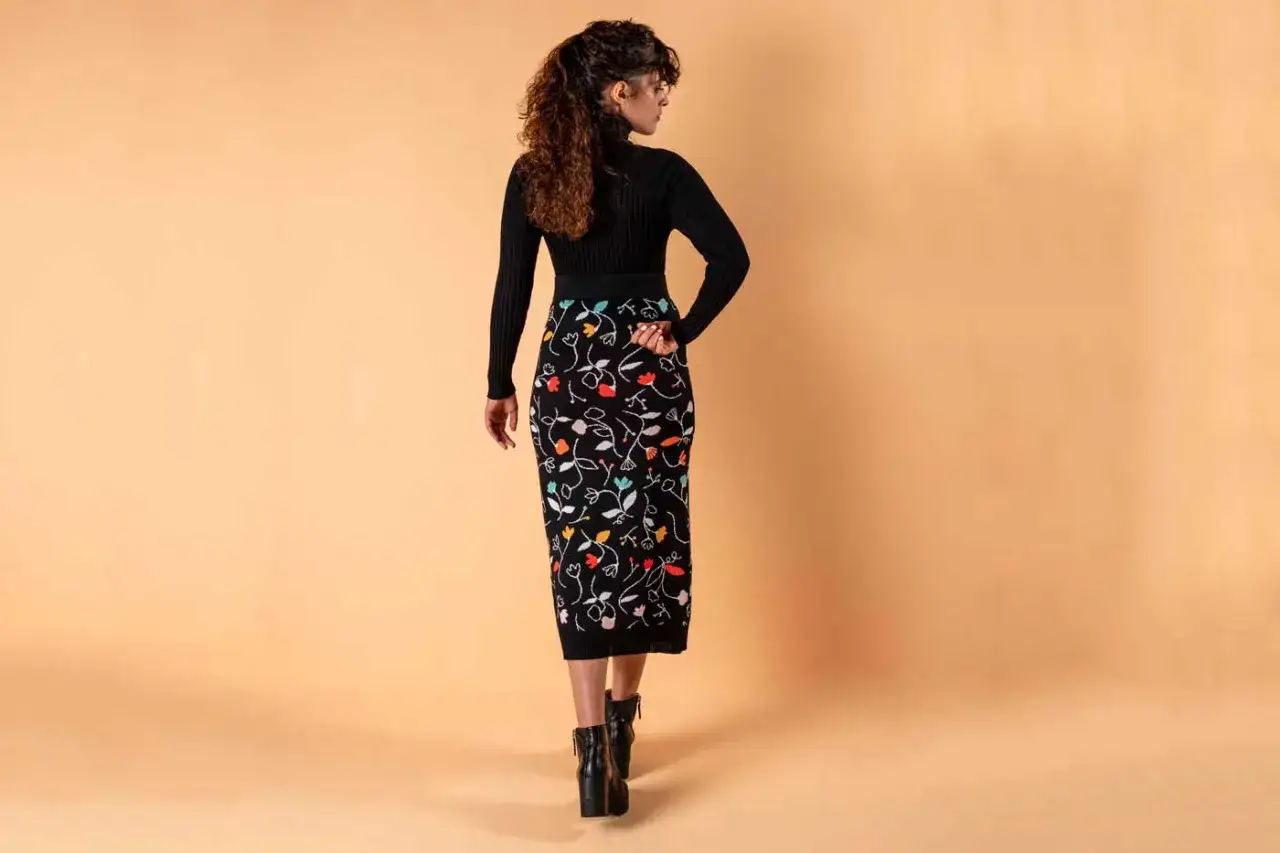 Mujer con falda lápiz negra estampada con flores de colores. Una de las muchas **tipos de faldas** que realzan la figura.