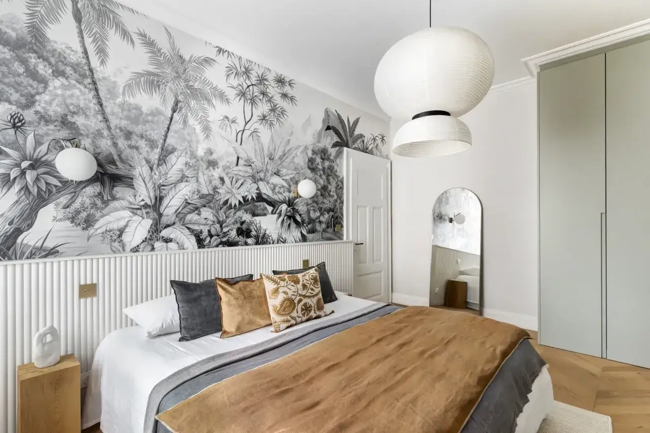 Une chambre avec une t&ecirc;te de lit en papier peint jungle. Le papier peint noir et blanc cr&eacute;e une ambiance tropicale.