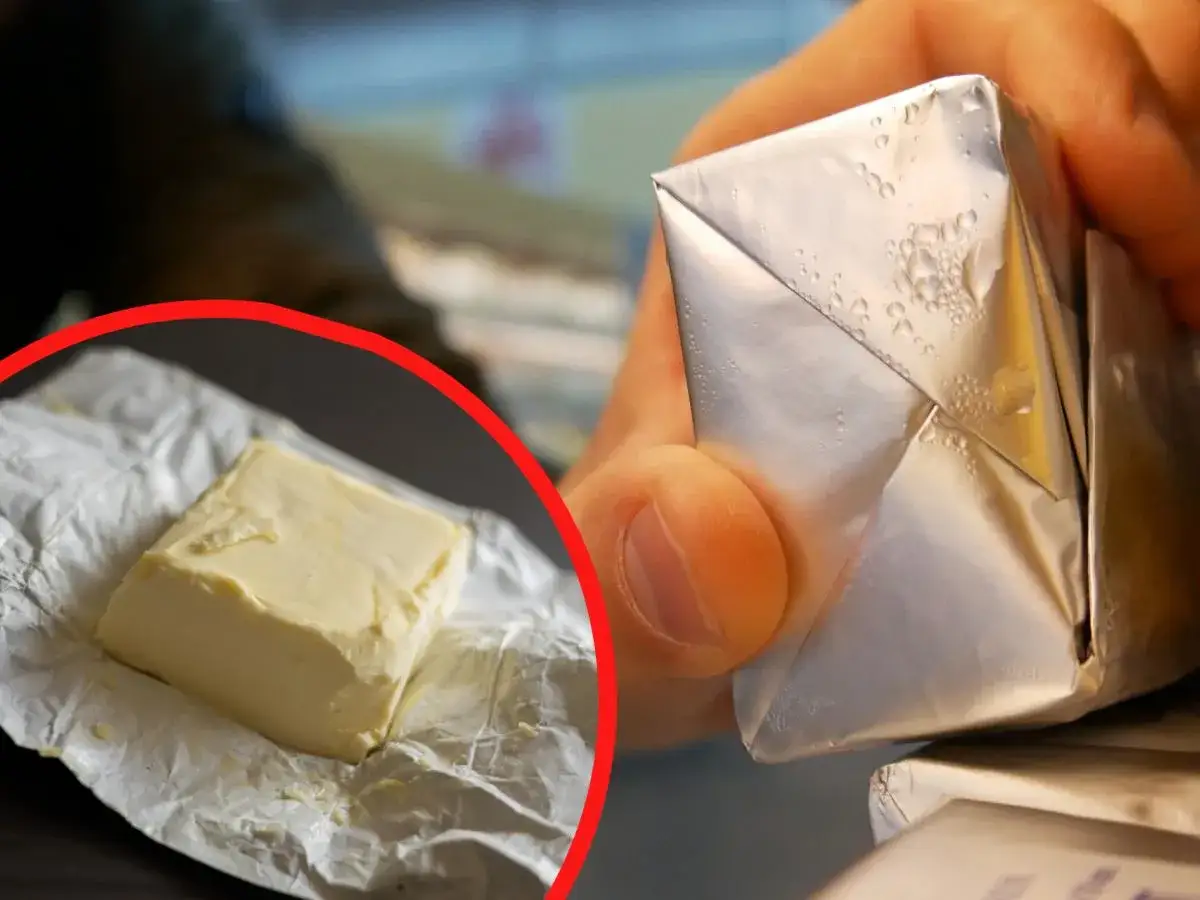 Masło w folii aluminiowej, z kroplami kondensacji, sugeruje, że można je mrozić. Kostka masła na papierze wewnątrz czerwonego okręgu.