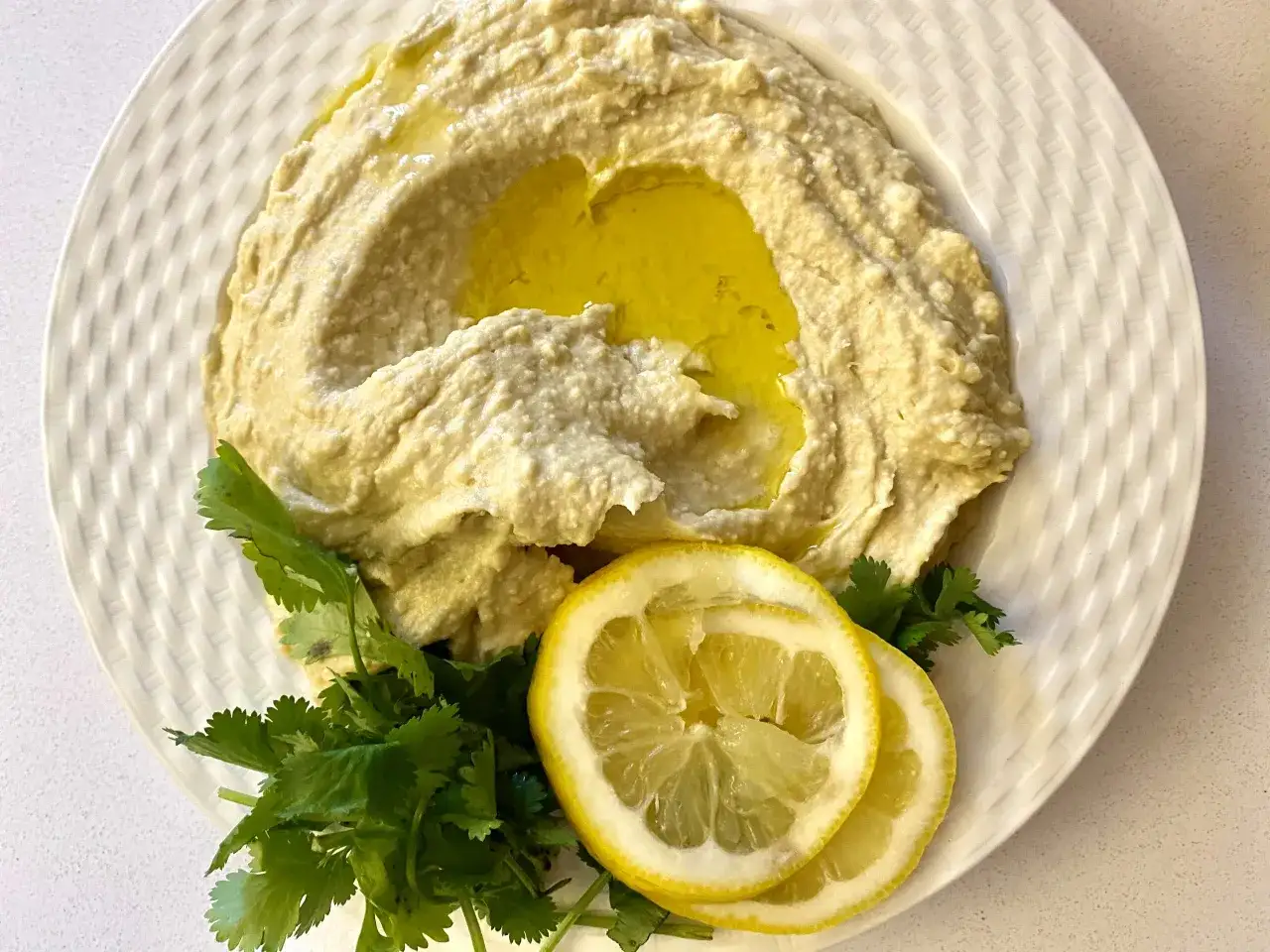 Kr&auml;mig hummus med olivolja, citronklyftor och f&auml;rsk koriander. Ett enkelt och gott hummus recept att njuta av.