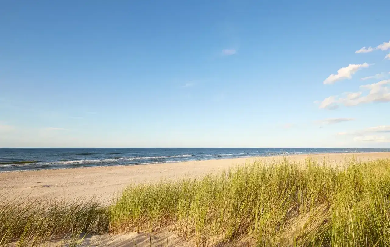 Plaża Słajszewo: piaszczysty brzeg, szum fal Bałtyku i wysoka trawa wydmowa pod błękitnym niebem.