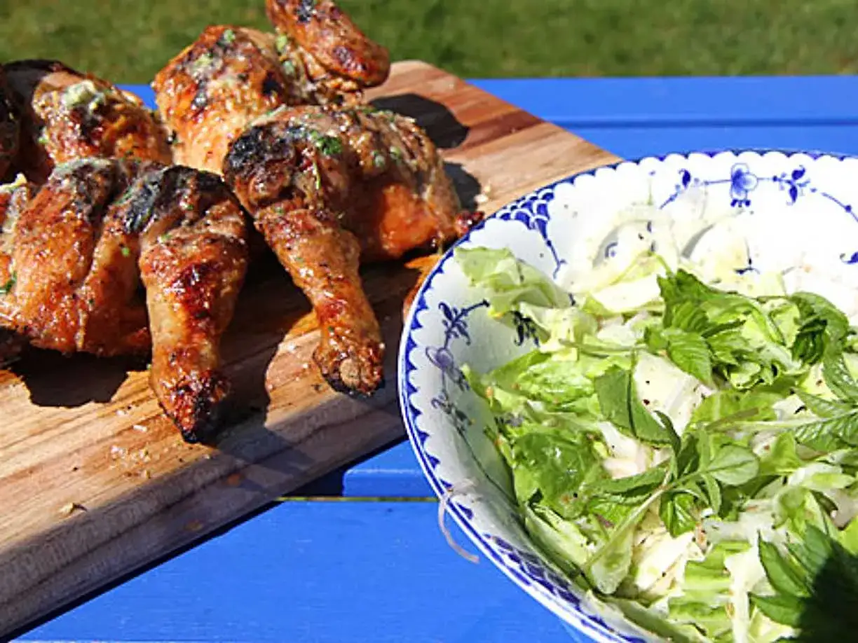 Saftig grillad kyckling på en skärbräda bredvid en fräsch sallad i en vacker skål. Perfekt sommarmat!