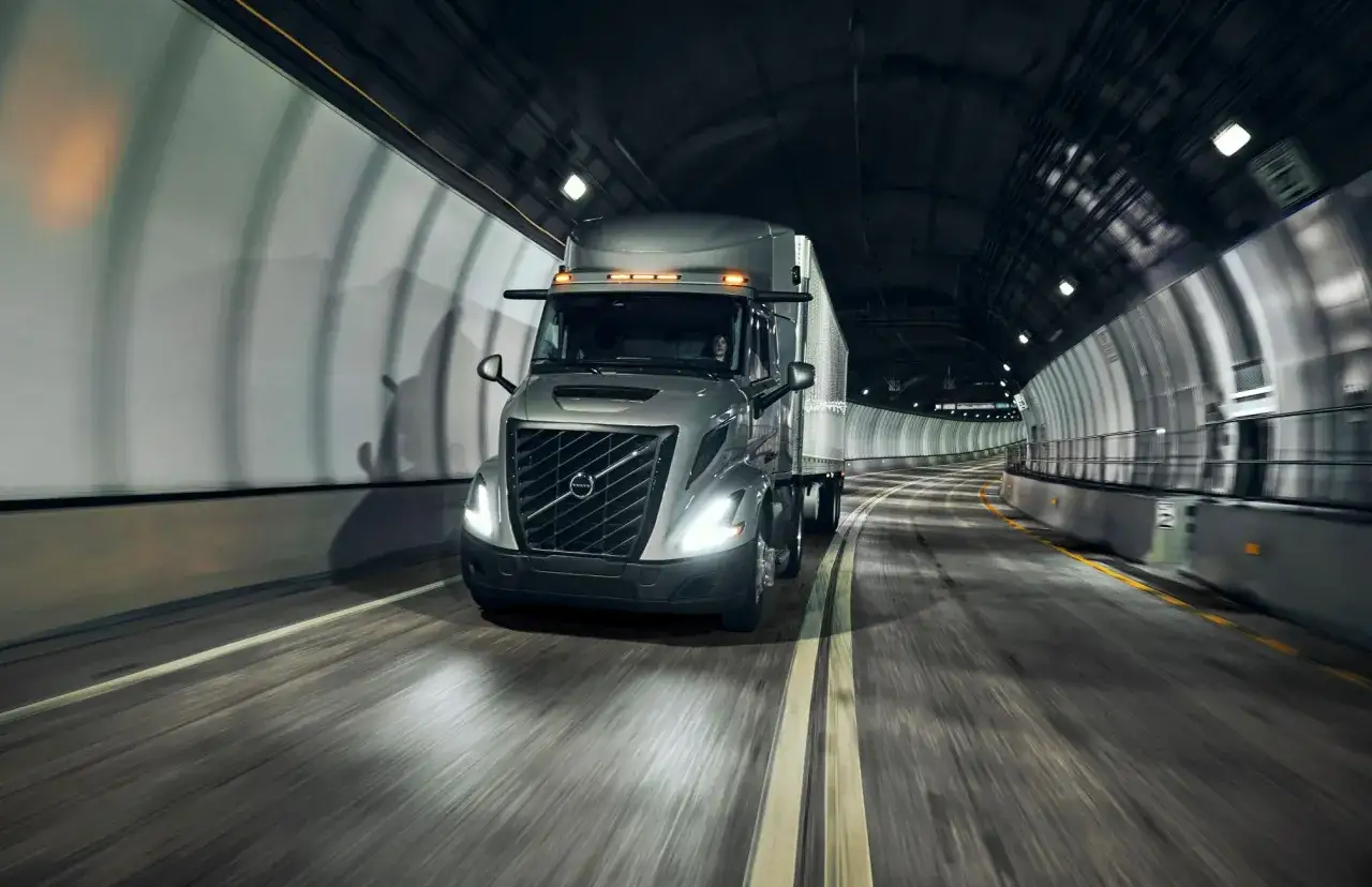 Un camion Volvo am&eacute;ricain traverse un tunnel sombre, ses phares illuminant la route.