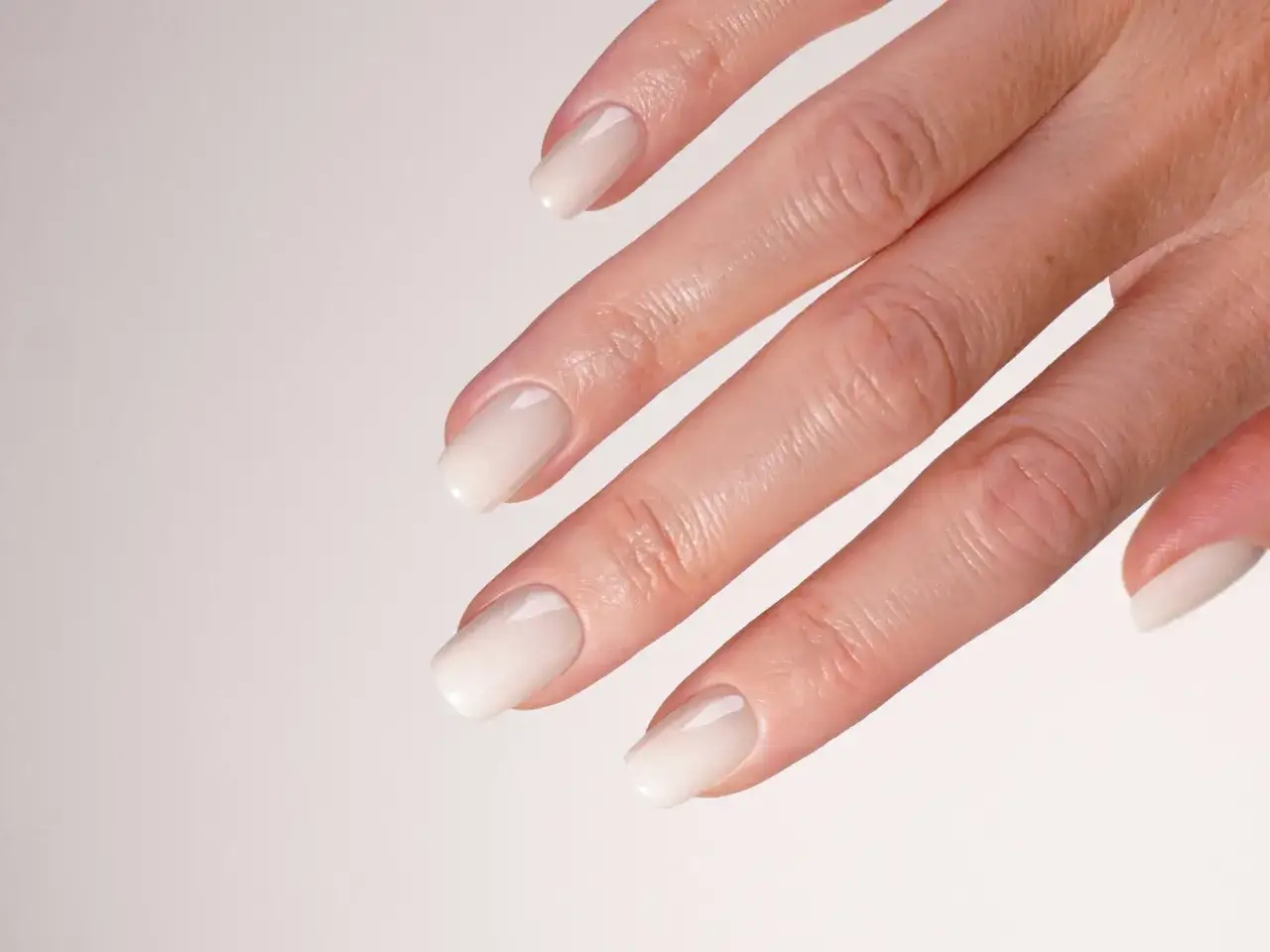 Mano con unghie curate e un delicato smalto sposa naturale, che esalta la bellezza discreta per un giorno speciale.