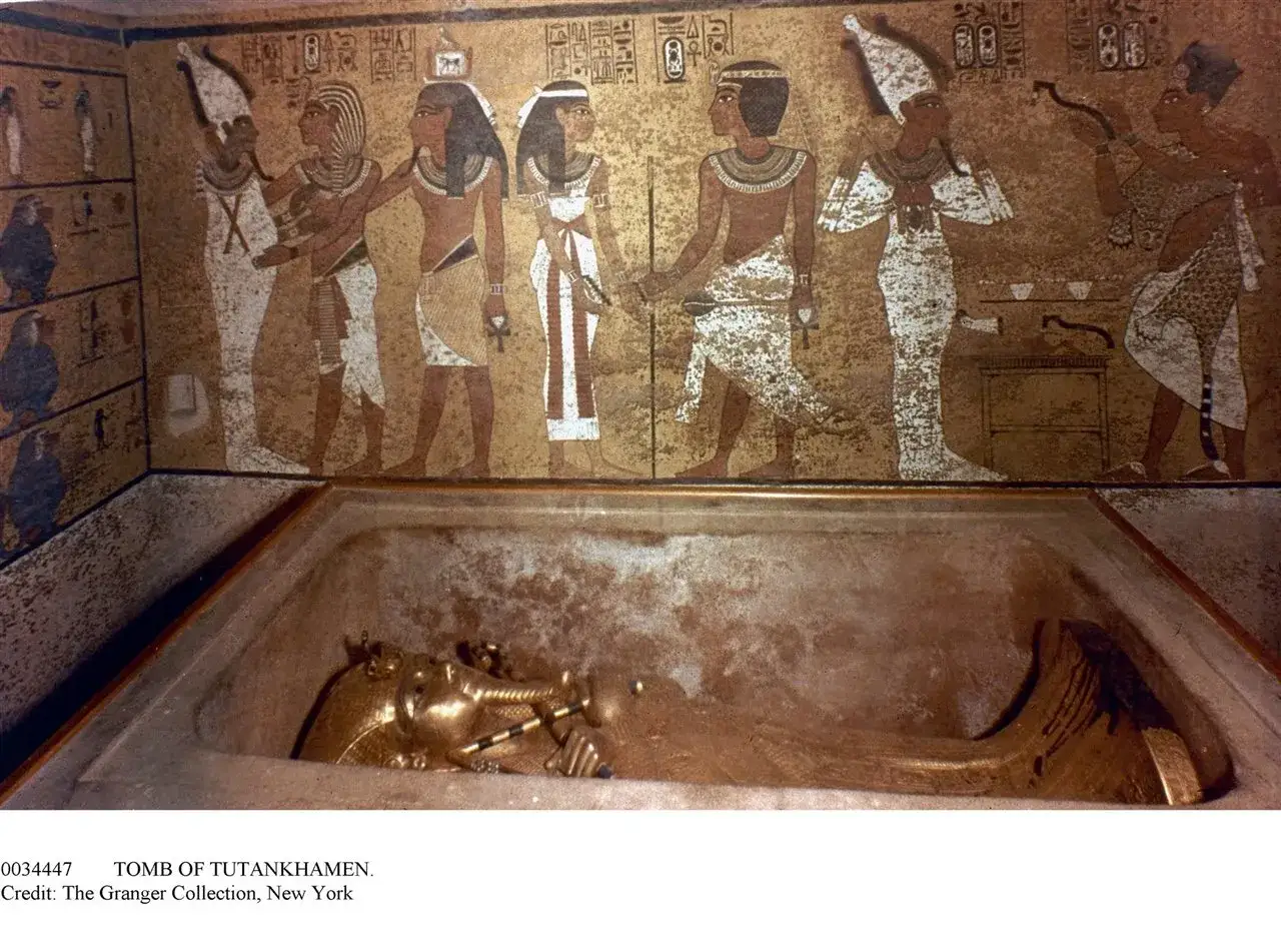 El sarc&oacute;fago dorado de Tutankam&oacute;n en su tumba, con murales que narran el descubrimiento de la tumba Tutankamon.
