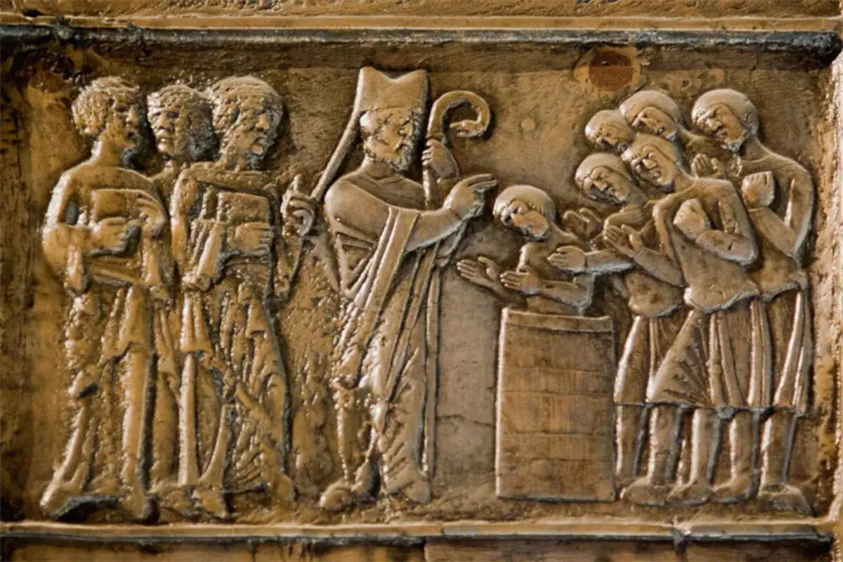 Rzeźba przedstawia scenę chrztu, symbolizującą początki chrześcijaństwa w Polsce. Biskup z pastorałem chrzci młodzieńca, a tłum ludzi patrzy z uwagą.