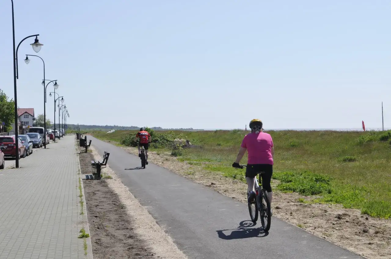 Dwie osoby na rowerach przemierzają malownicze pomorskie trasy rowerowe wzdłuż wybrzeża.