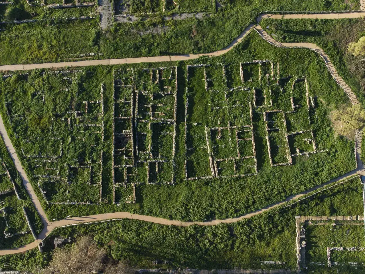 Vista aerea della necropoli centocamere, con rovine antiche e sentieri che attraversano l'erba alta.