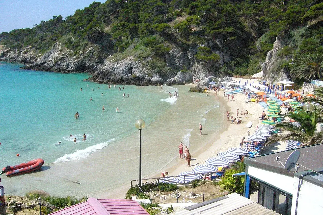 Spiagge delle Isole Tremiti raggiungibili a piedi, con gente che nuota e prende il sole sotto ombrelloni colorati.