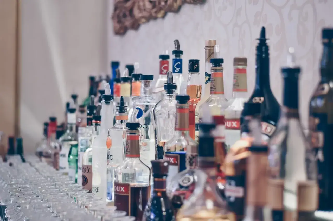 Rząd butelek wódek świata i kieliszków, idealny do tego, jak zaplanować bar tematyczny z wódkami świata na event.