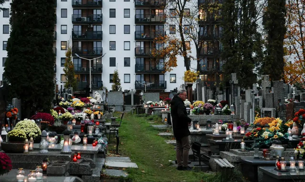 Mężczyzna na cmentarzu, wśród grobów i zniczy. Czy warto wykupić miejsce na cmentarzu za życia rezerwacja? Refleksja nad przyszłością.