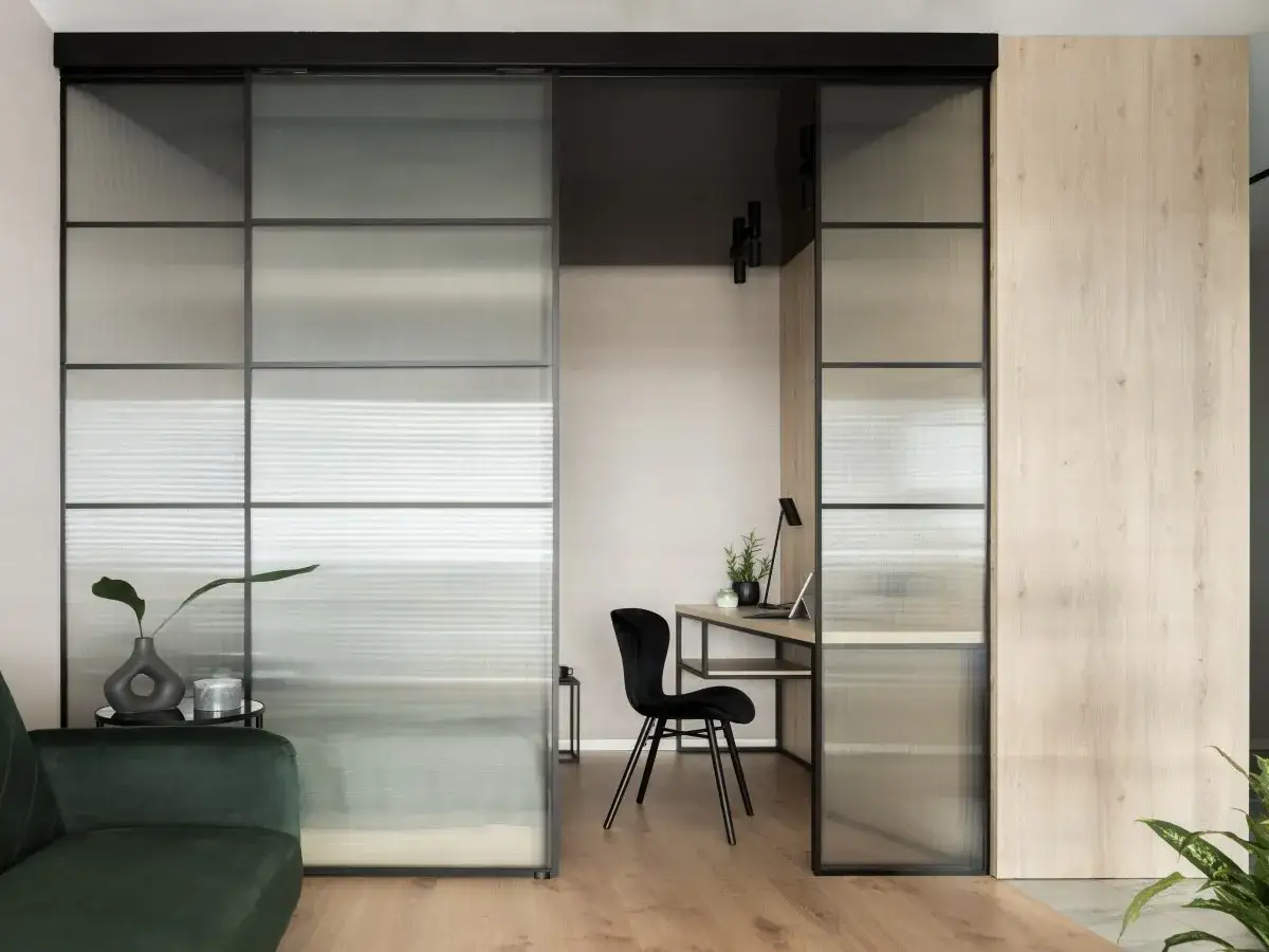 Panel de vidrio y madera para dividir sal&oacute;n en dos ambientes, creando un espacio de trabajo acogedor.