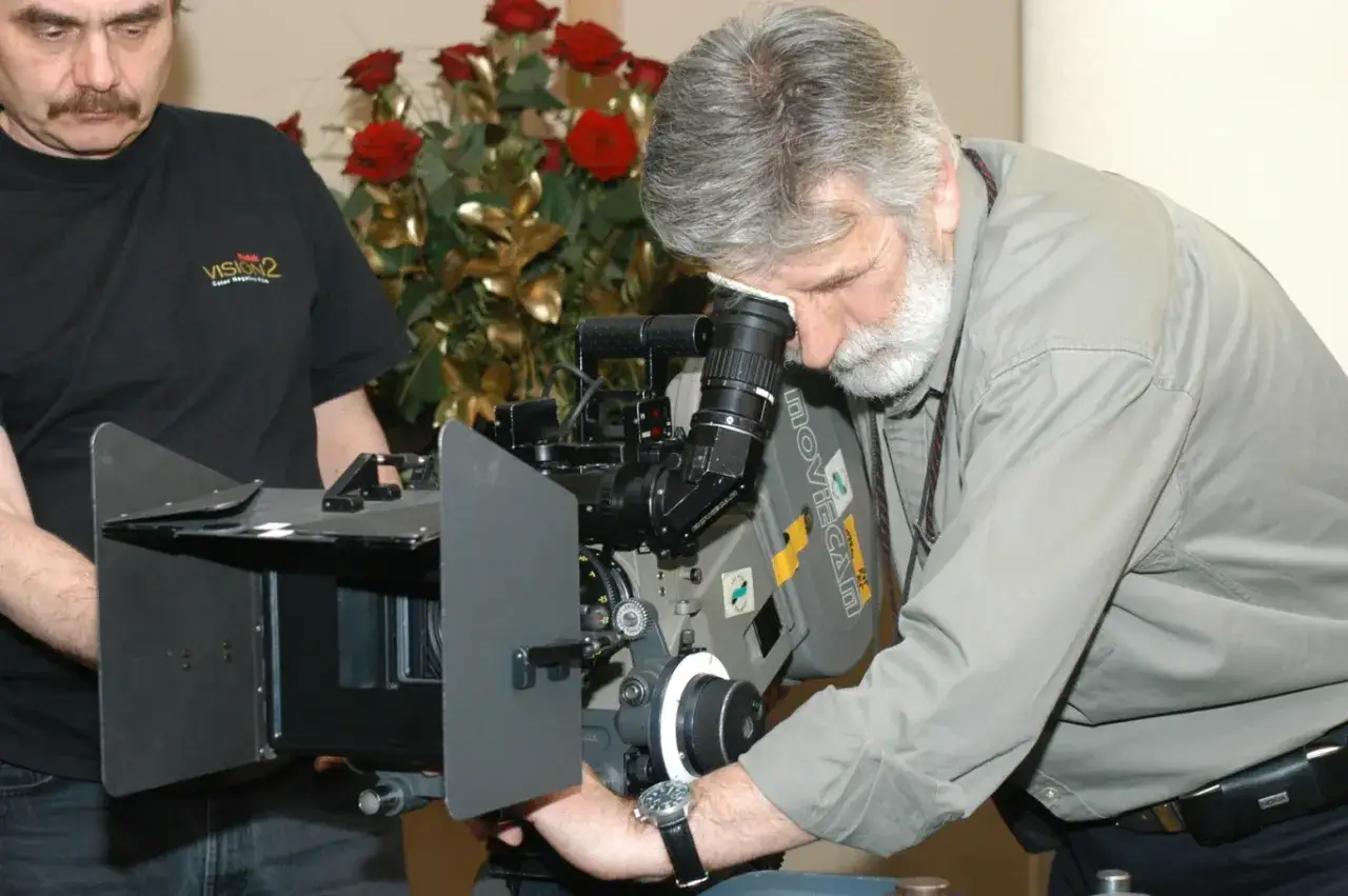 Edward Kłosiński, mistrz kamery, pochyla się nad profesjonalnym sprzętem filmowym.