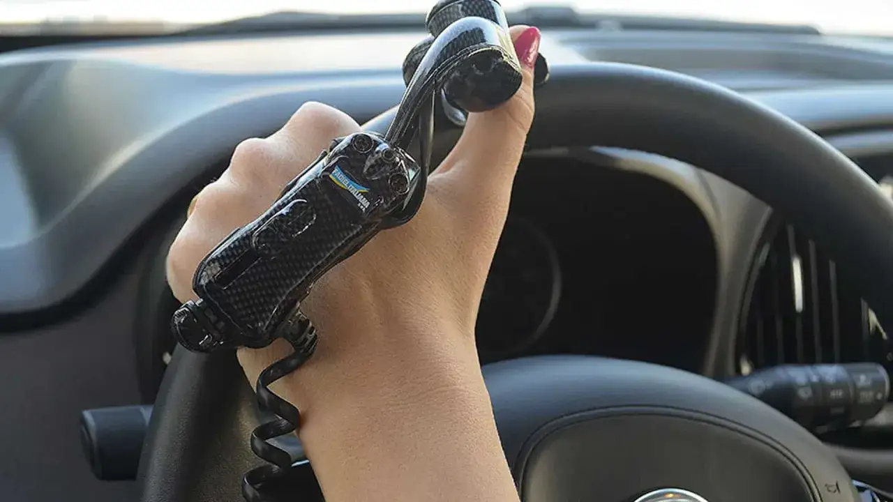 Mano che impugna un pomello per volante, parte di un allestimento auto per facilitare la guida.