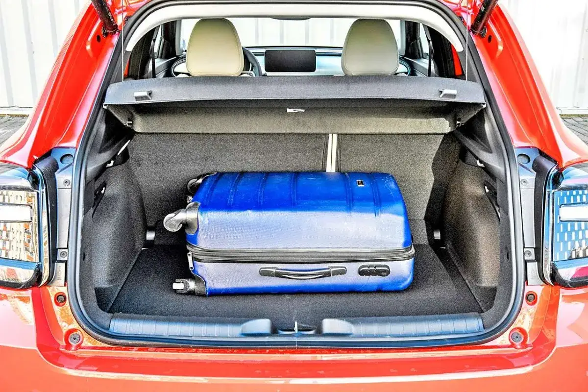 Bagażnik czerwonego Fiata 600 mieści niebieską walizkę. Sprawdź aktualną fiat 600 cena i wybierz się w podróż!
