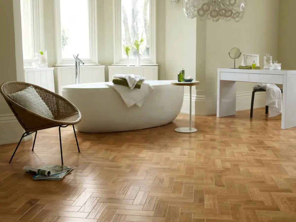 Ba&ntilde;o moderno con ba&ntilde;era exenta y suelo de parquet en espiga, mostrando como colocar el parquet horizontal o vertical para un acabado elegante.