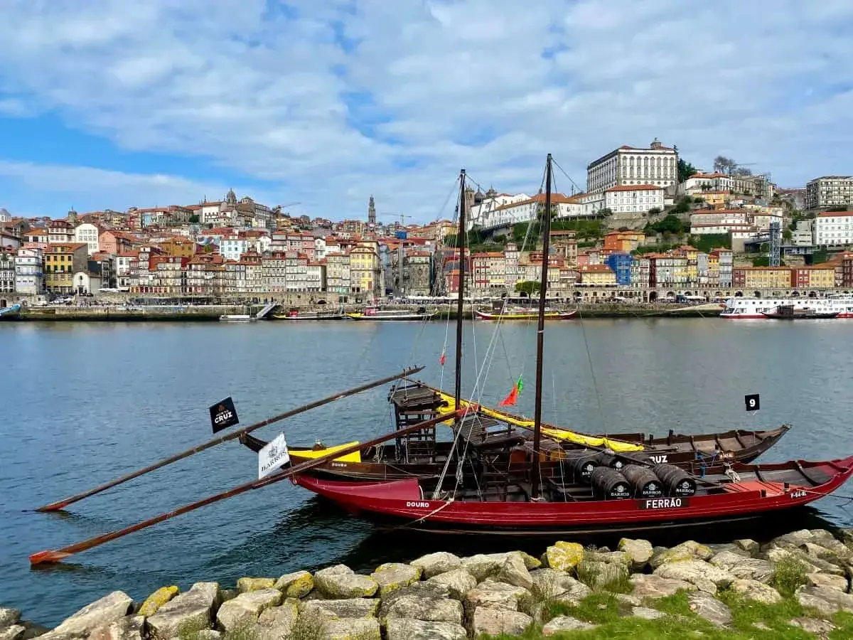Tradycyjne łodzie rabelo z beczkami wina porto Ferreira na rzece Douro, z widokiem na kolorowe miasto Porto.