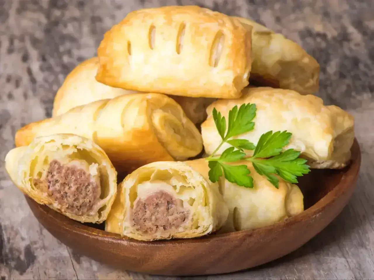 Pyszne, złociste ciasto francuskie z mięsnym farszem, ułożone w drewnianej misce. Ile piec ciasto francuskie?