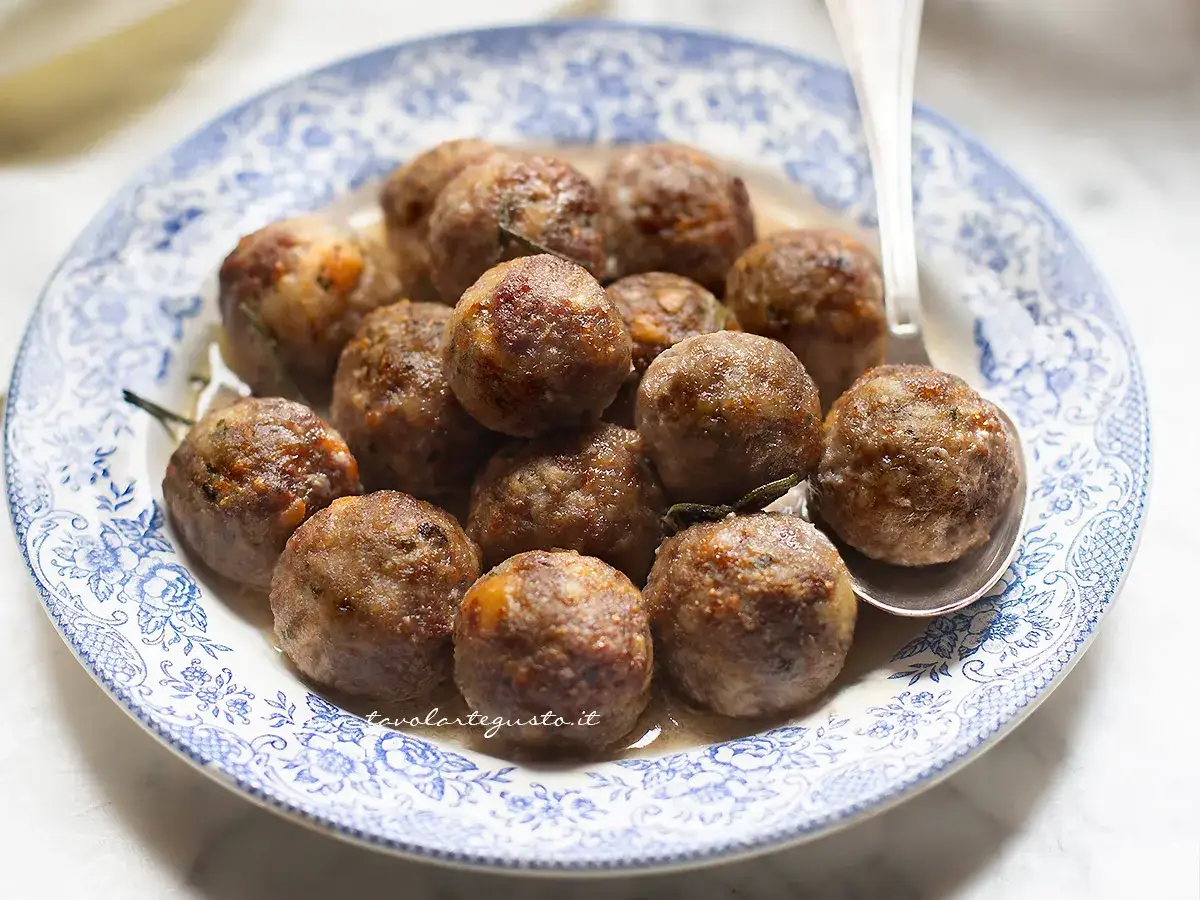 Polpette dorate e succulente in friggitrice ad aria, servite su un piatto di ceramica blu e bianco.