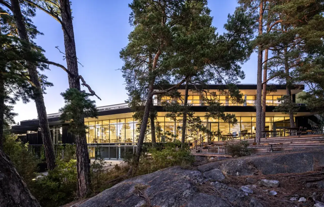 Artipelag museum, en modern byggnad med stora fönster, omgiven av tallar och klippor vid vattnet.
