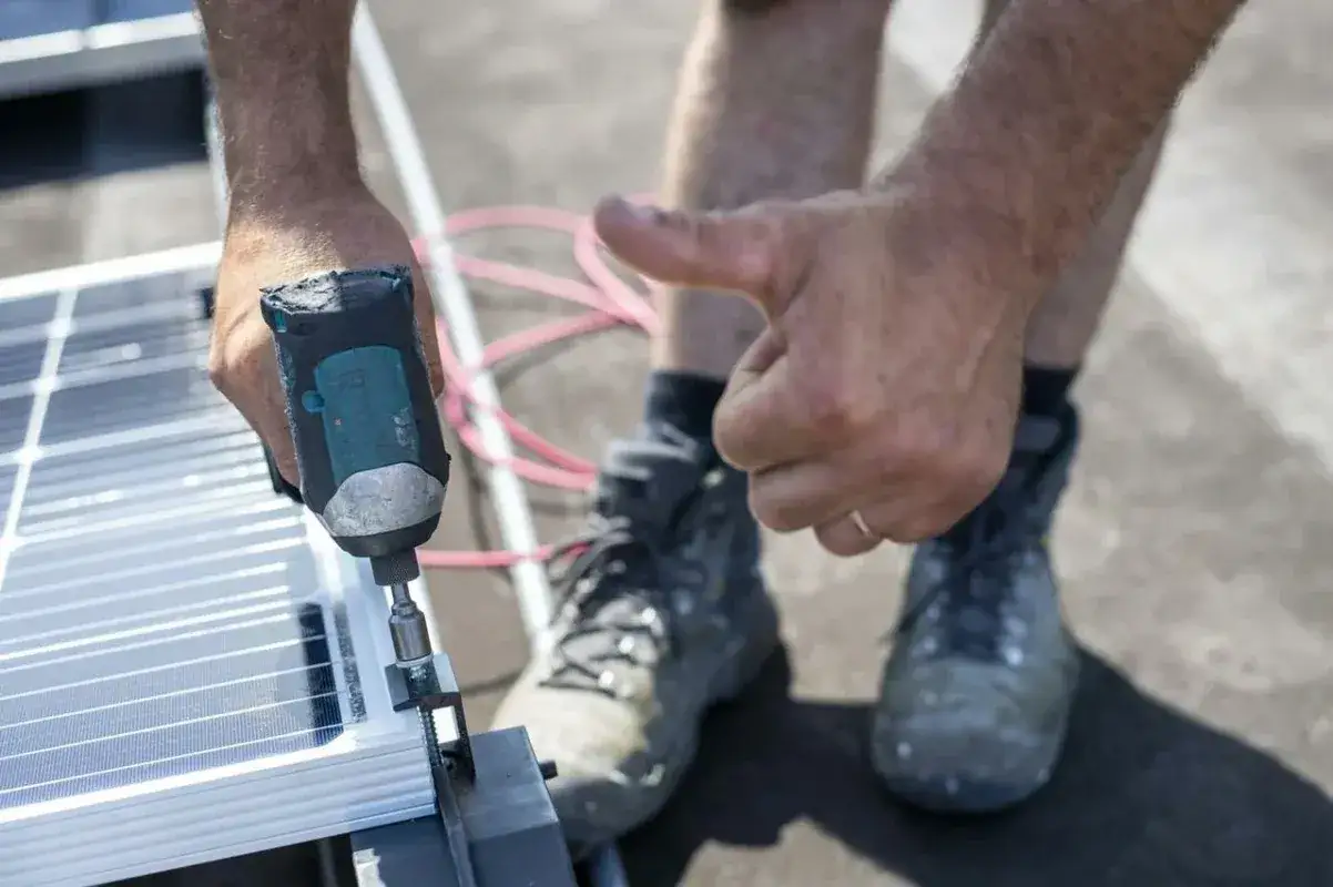 Instalator montuje panele fotowoltaiczne, używając wkrętarki. Kciuk w g&oacute;rę sugeruje, że problem z afci fault jak wyłączyć został rozwiązany.