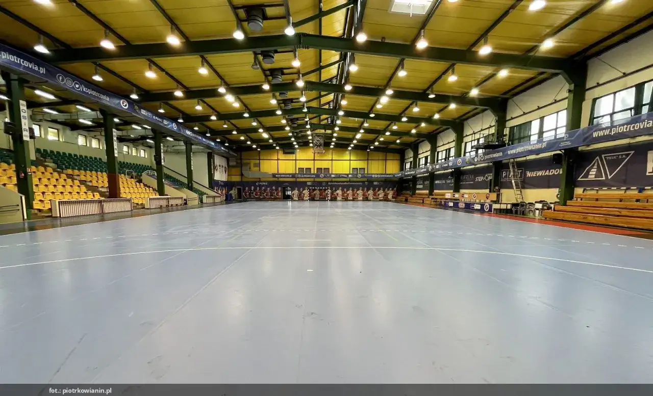 Pusta hala sportowa MKS Piotrcovia z trybunami i bandami reklamowymi.