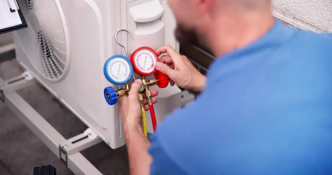 Técnico revisa manómetros para cargar gas aire acondicionado.