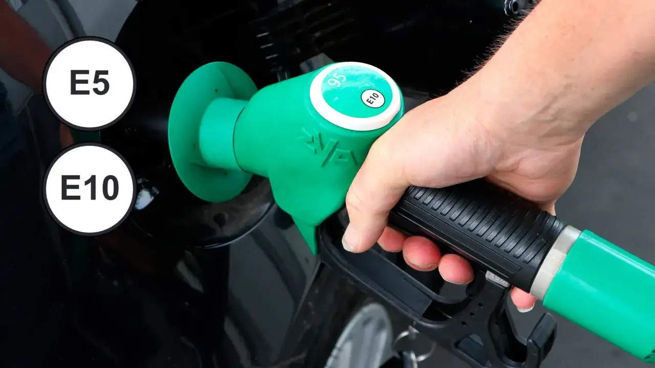 Hand h&aring;ller en pump f&ouml;r e5 bensin. Bredvid syns skyltar f&ouml;r E5 och E10.