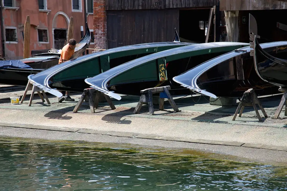 Diverse imbarcazioni tipiche veneziane, gondole in fase di manutenzione, si stagliano sull'acqua.