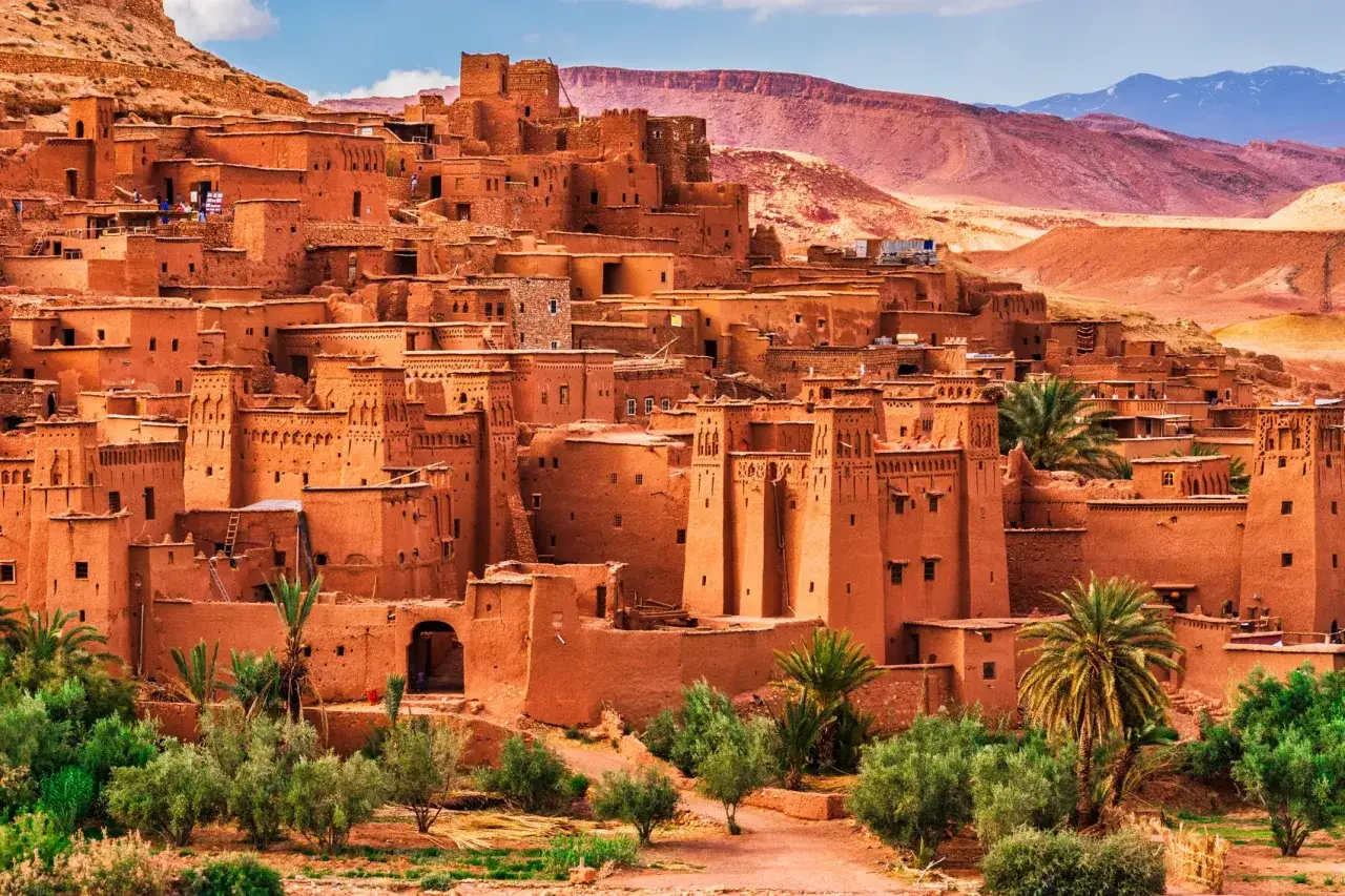 Ait Ben Haddou, Maroko co warto zobaczyć. Starożytna kasba z gliny, wpisana na listę UNESCO, w otoczeniu zieleni i pustynnych krajobrazów.