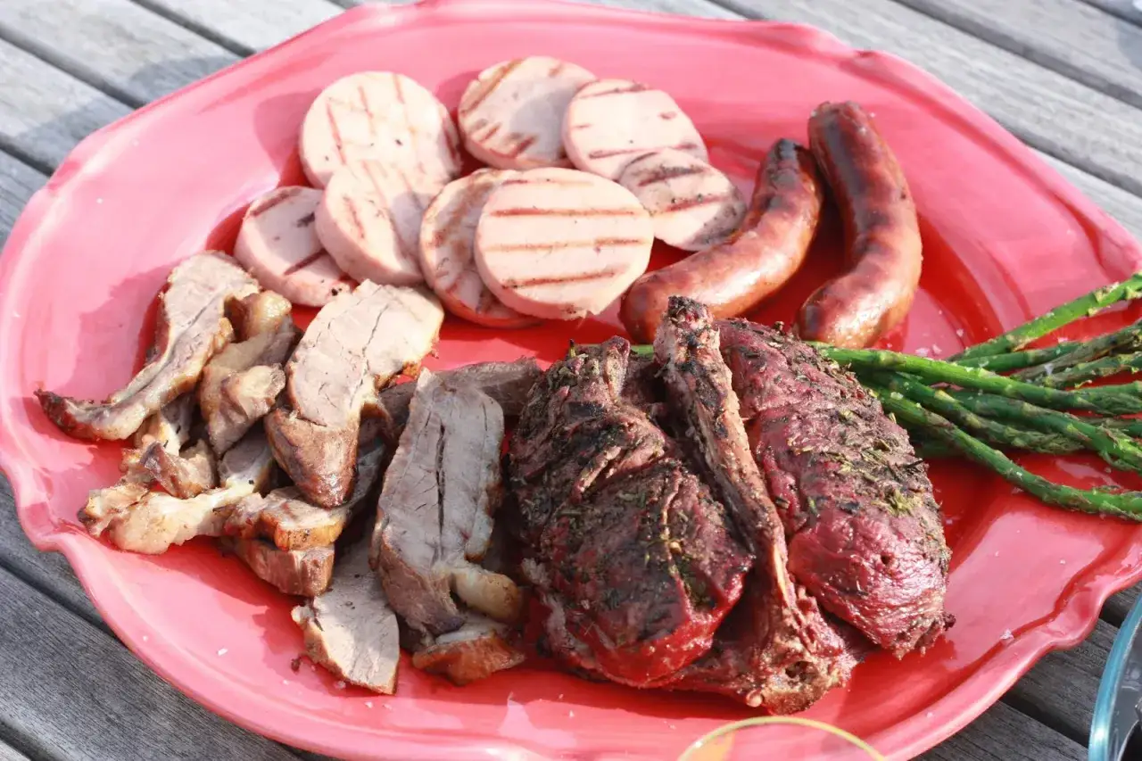 En stor r&ouml;d bricka med grillad r&aring;djur, korv, grillad korv och sparris. En h&auml;rlig sommarm&aring;ltid!