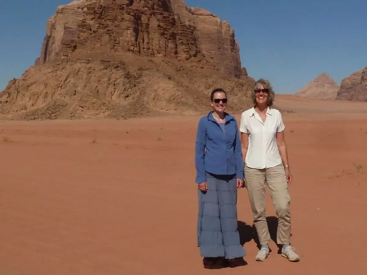 Zwei Frauen stehen in der W&uuml;ste Jordaniens vor beeindruckenden Felsen. Perfekt f&uuml;r die Packliste Jordanien: leichte Kleidung, Sonnenbrillen und bequeme Schuhe.