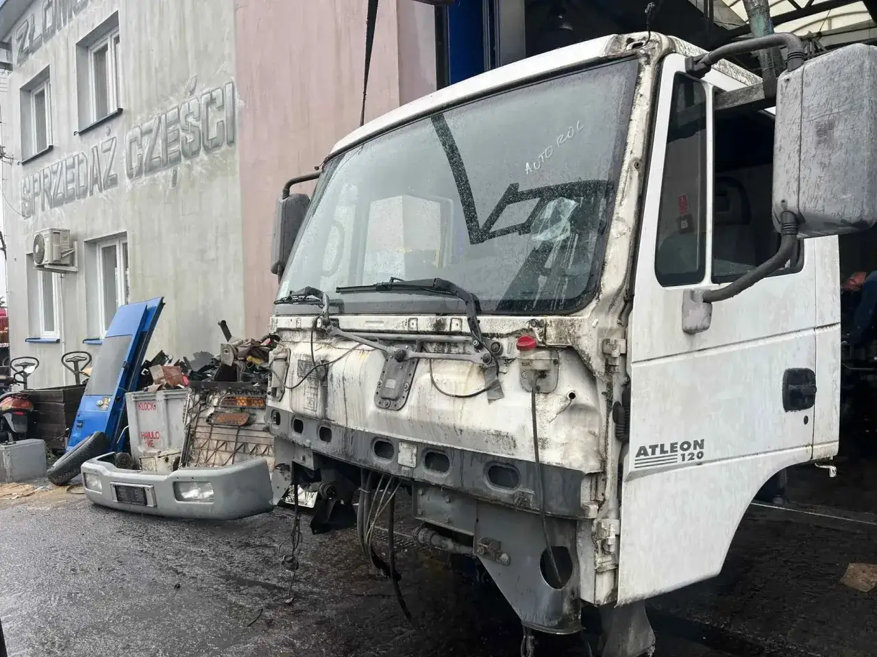 Biała kabina ciężarówki Nissan **Atleon** 120, zdemontowana, stoi na placu z częściami.