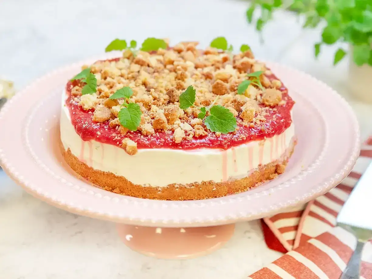 En krämig rabarber cheesecake med smulig topping och färska myntablad. Perfekt för sommaren!