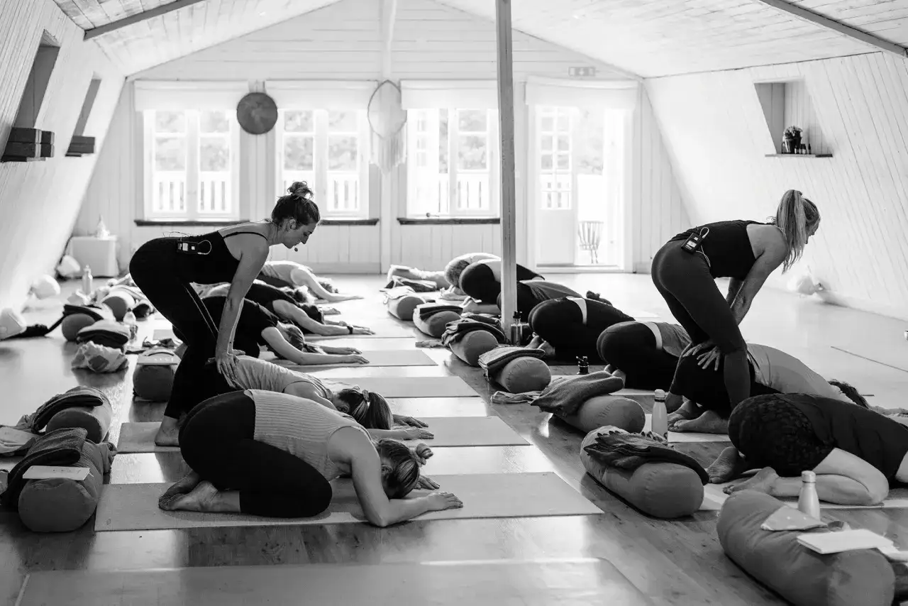 Grupp i barnets position under yoga. En instruktör guidar. Drömmer om en yoga utbildning csn.