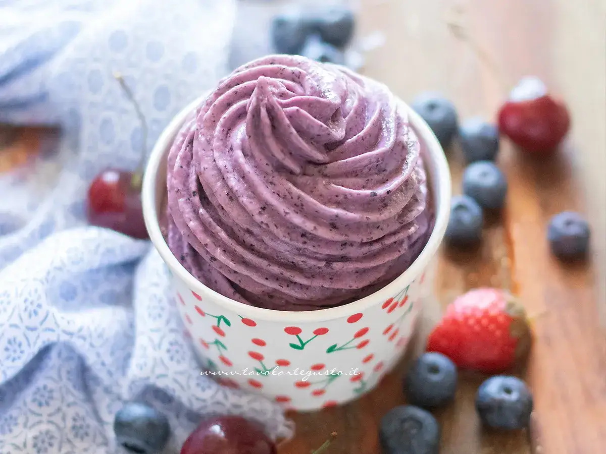 Delizioso gelato viola cremoso, un'idea perfetta per dolci senza zucchero, con mirtilli e ciliegie fresche intorno.