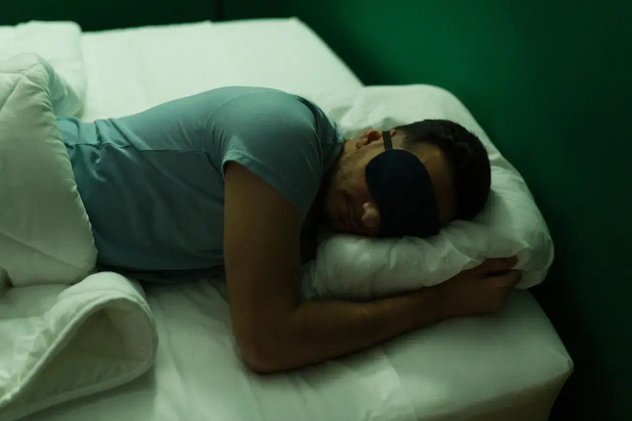 A man sleeps with an eye mask, nestled in white sheets. Is 6 hours of sleep enough for him to feel rested?