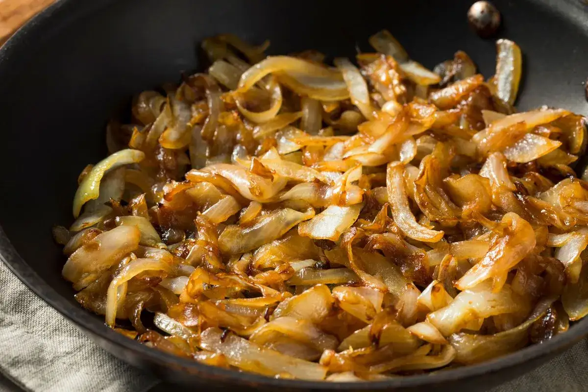 Cipolle caramellate in padella, dorate e succulente, pronte per arricchire ogni piatto.