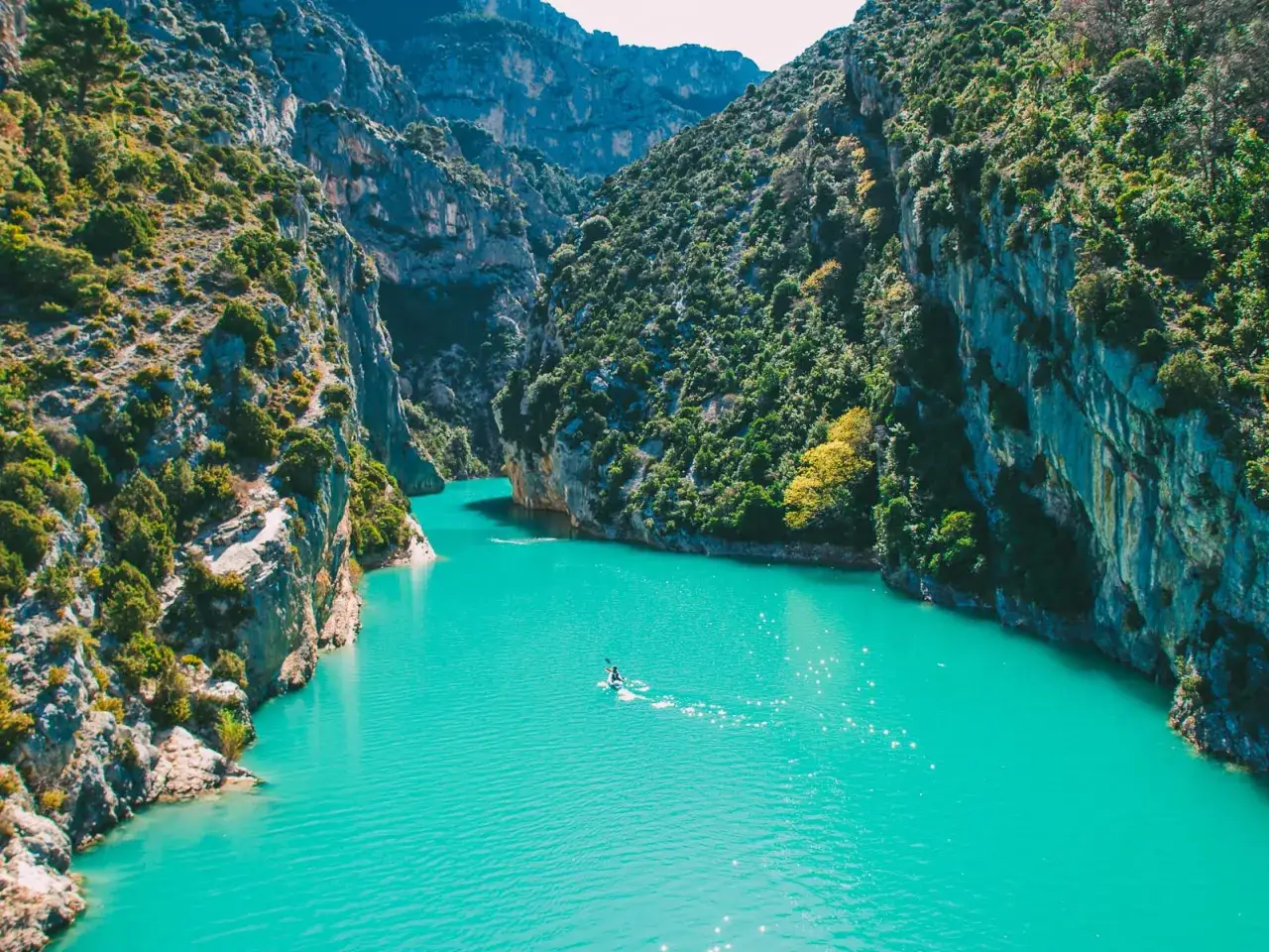 Türkisblaue Schlucht mit einem Paddler, ein Traumziel für fernwanderwege in Frankreich.