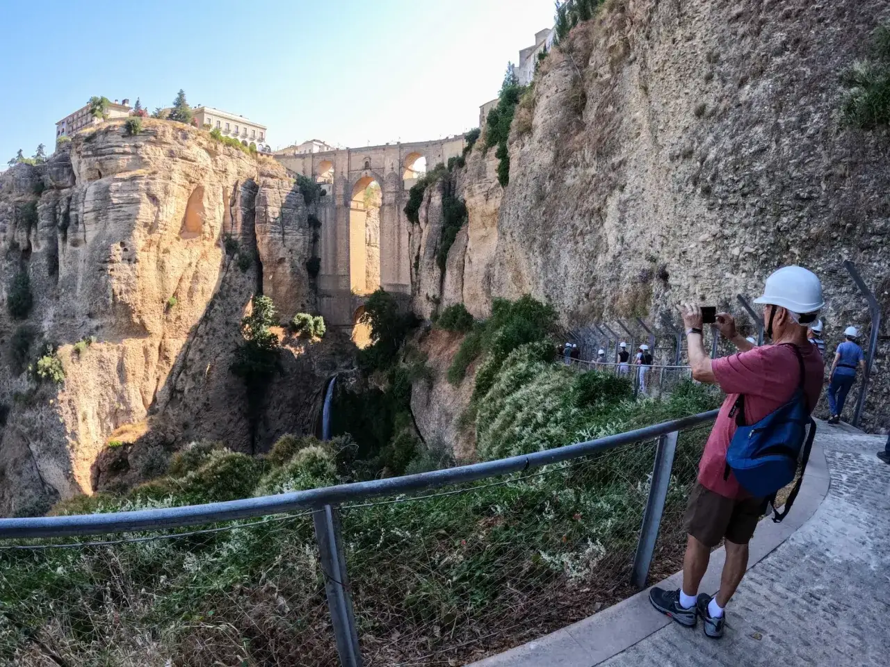Turista toma foto del Puente Nuevo y la cascada. Disfruta de las rutas por Ronda, un paisaje impresionante.