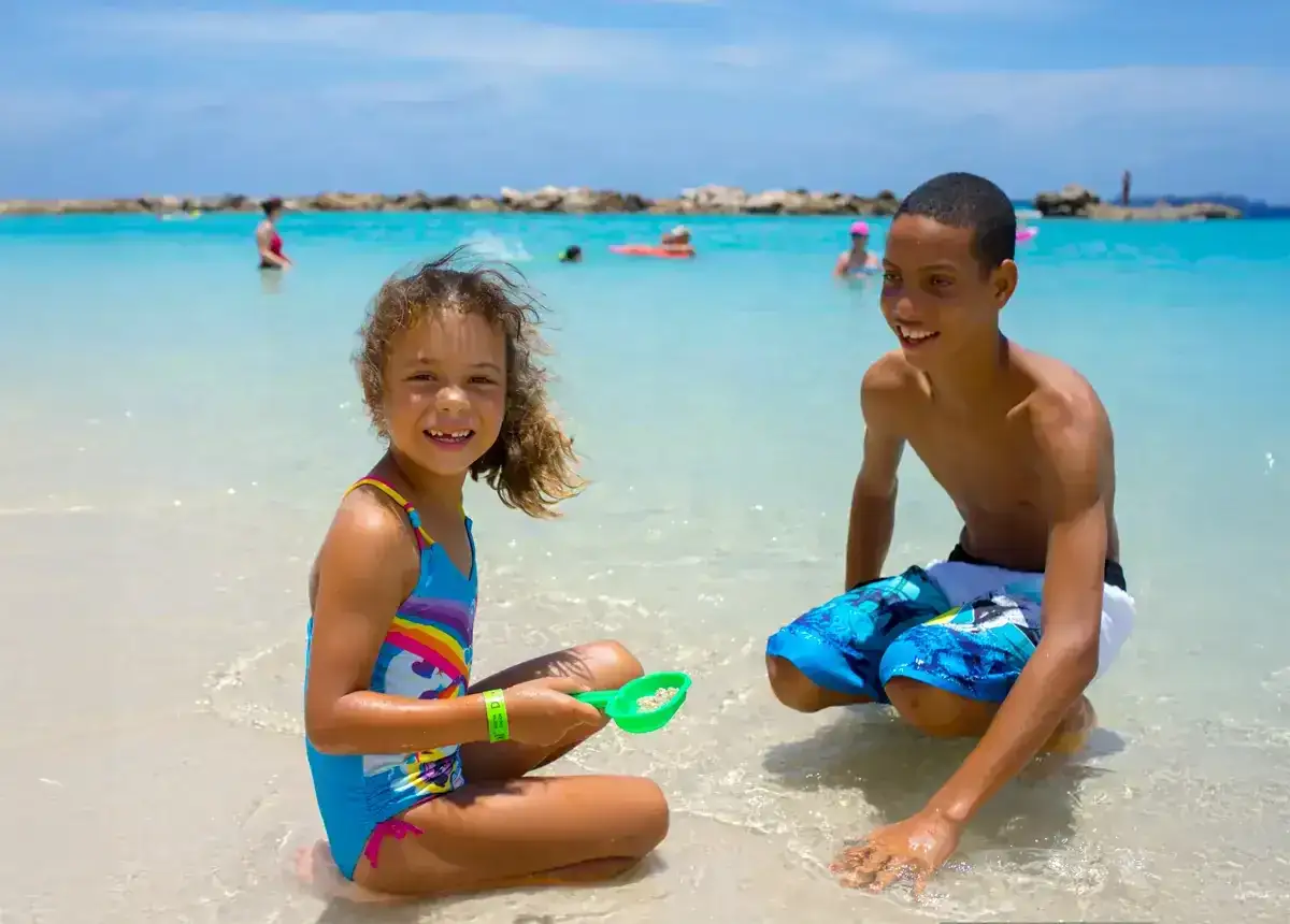 Dos niños disfrutan de un día soleado en la playa de la República Dominicana, jugando en las aguas cristalinas.