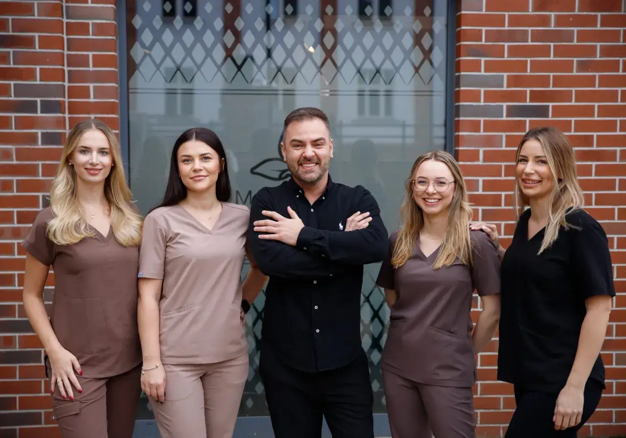 Zespół medyczny w uniformach przed budynkiem kliniki dermatologii estetycznej.