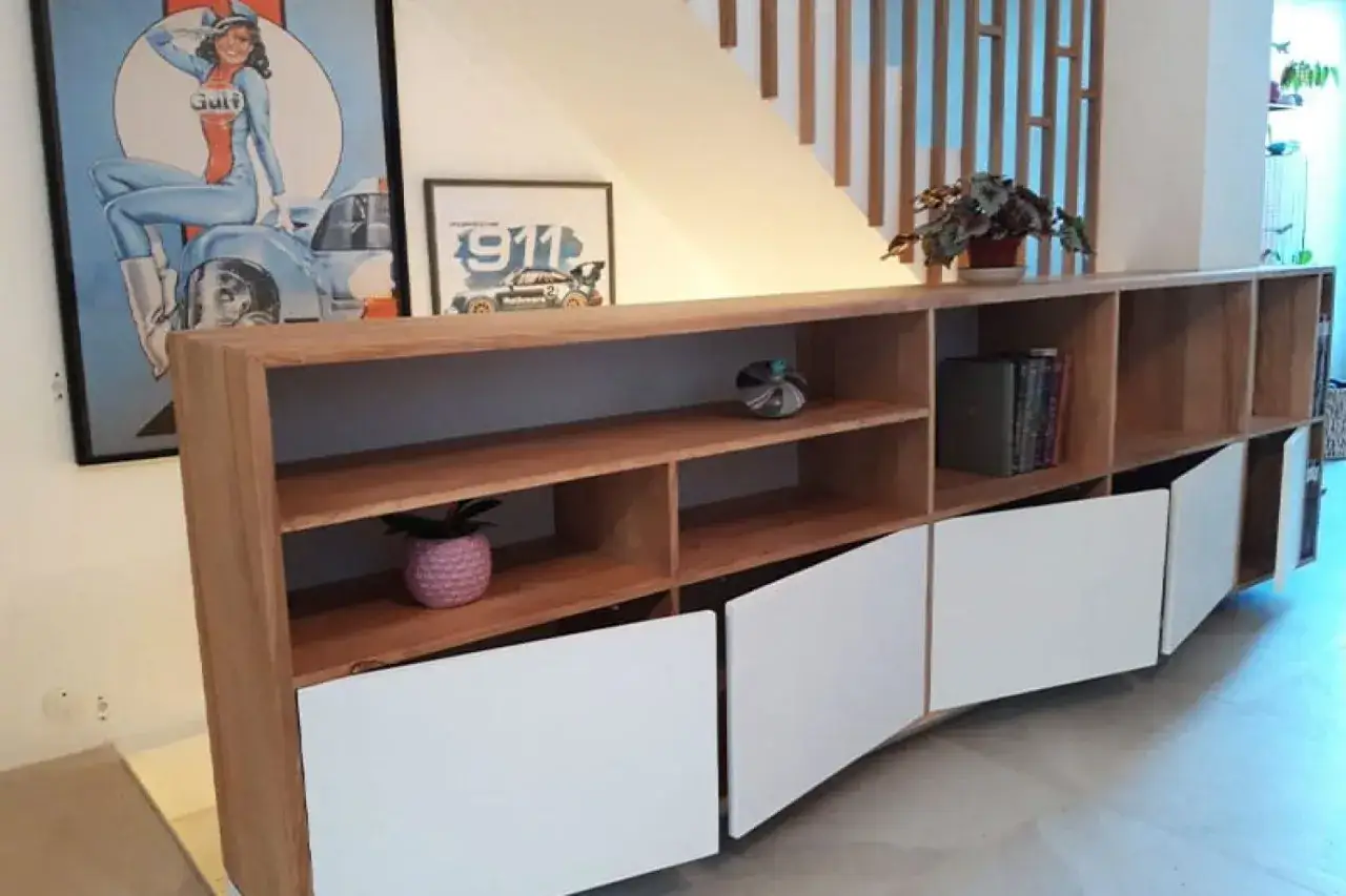 Meuble bas en bois, œuvre d'un menuisier ébéniste, avec portes blanches incurvées et étagères ouvertes.