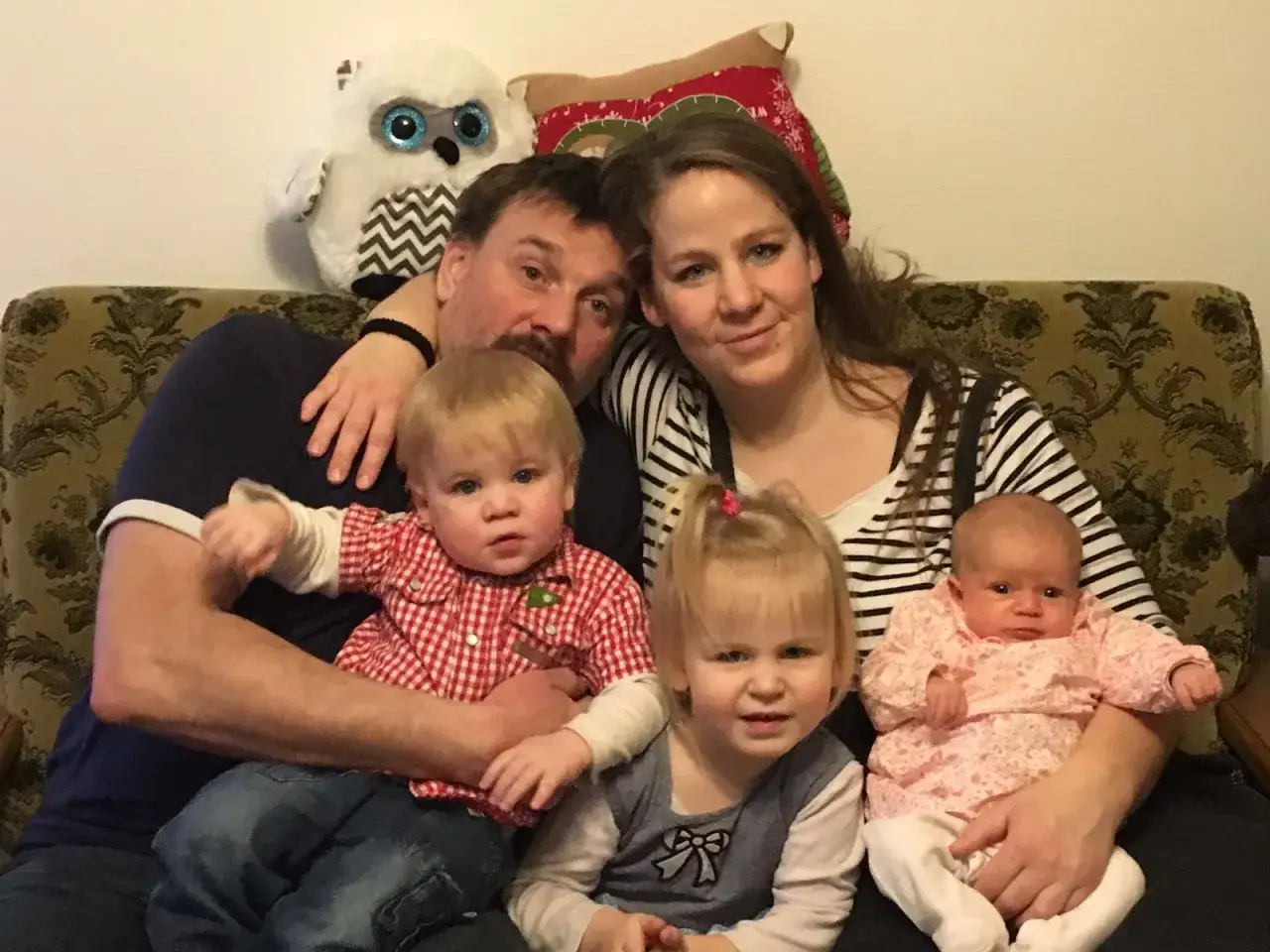 Glückliche Familie mit drei Kindern, die sich auf eine zweisprachige Erziehung freuen. Ein Plüsch-Eule wacht über sie.