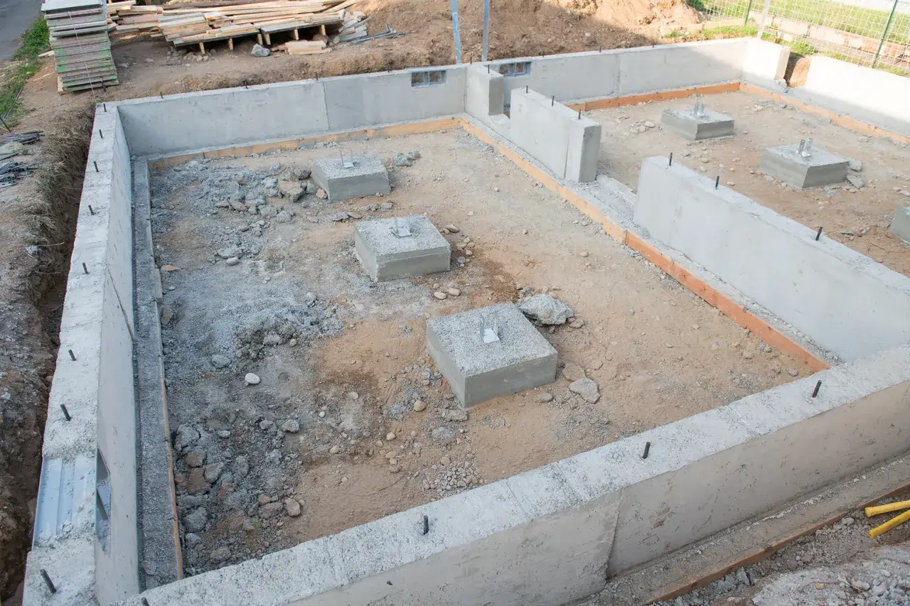 Fundament budowy z betonowych bloczków, z widocznymi słupkami i zbrojeniem.