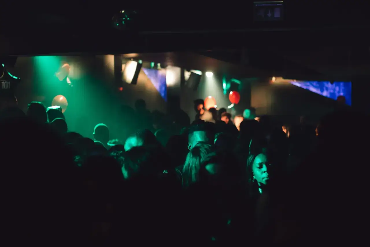 Folk dansar i m&ouml;rkret p&aring; en nattklubb i Stockholm, upplysta av gr&ouml;na och r&ouml;da lampor.