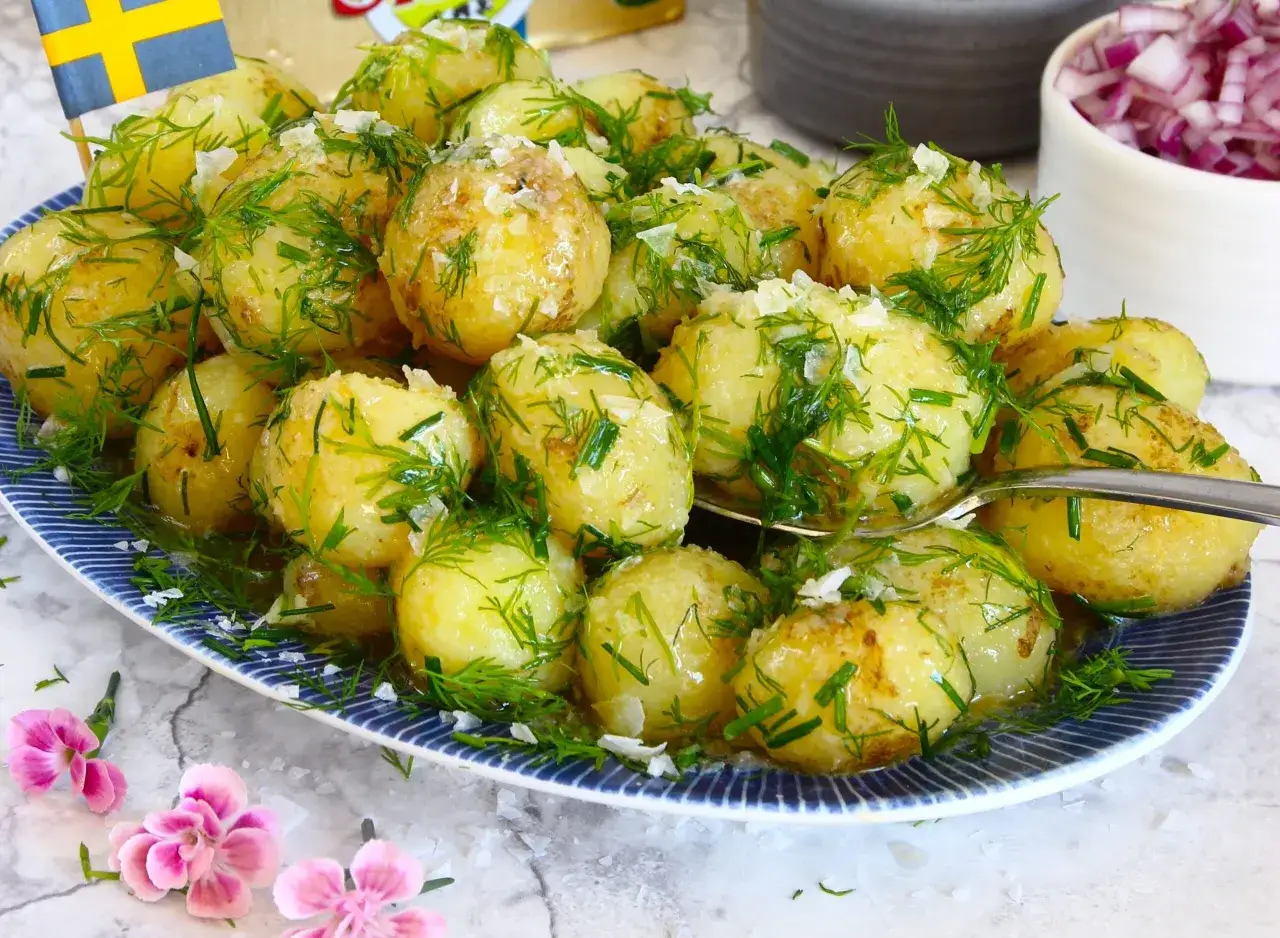 En tallrik med dillkokt potatis, toppad med f&auml;rsk dill och flingsalt. En svensk flagga sticker upp bland potatisen.